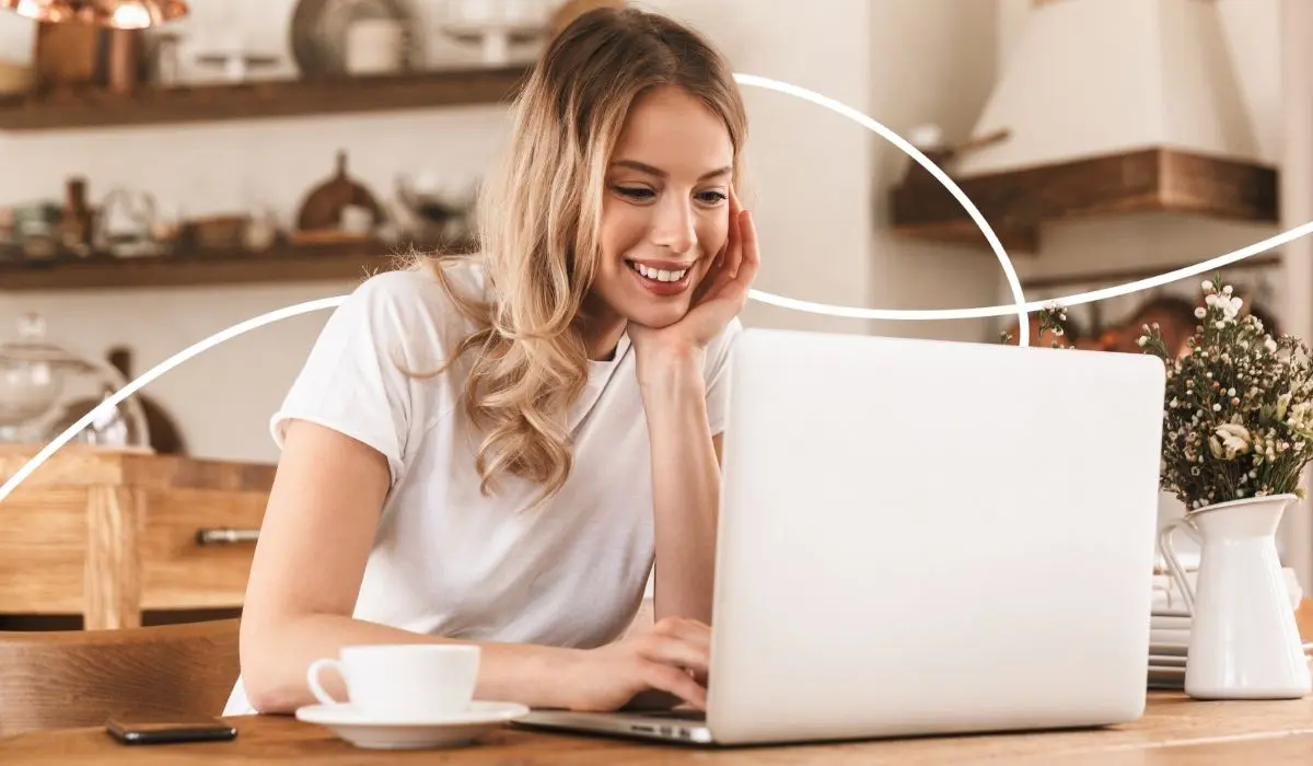 Junge Frau sitzt an einem Tisch und arbeitet an freudig an einem Laptop auf dem sie Loyalty Lösungen vergleicht.