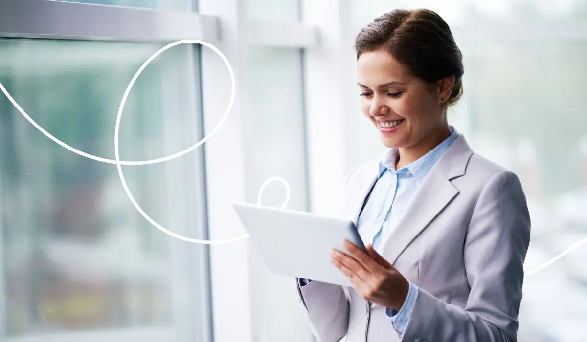 Geschäftsfrau im hellen Büro lächelt beim Blick auf ihr Tablet – Marketing Automation in der Kundenbindung.