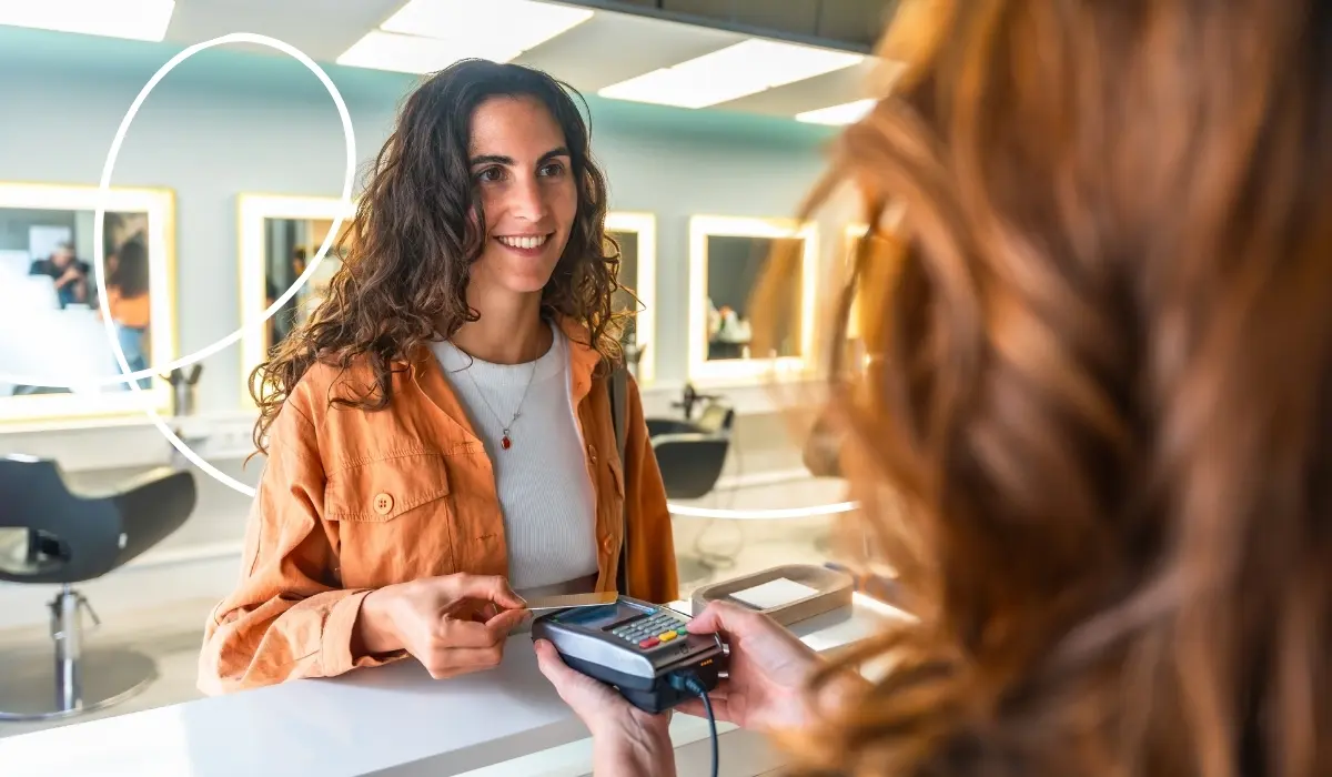Kundin hält ihre NFC-Kundenkarte an ein Lesegerät an der Kasse im Friseursalon