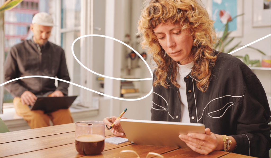 Frau sitzt an einem Tisch und arbeitet mit einem Tablet
